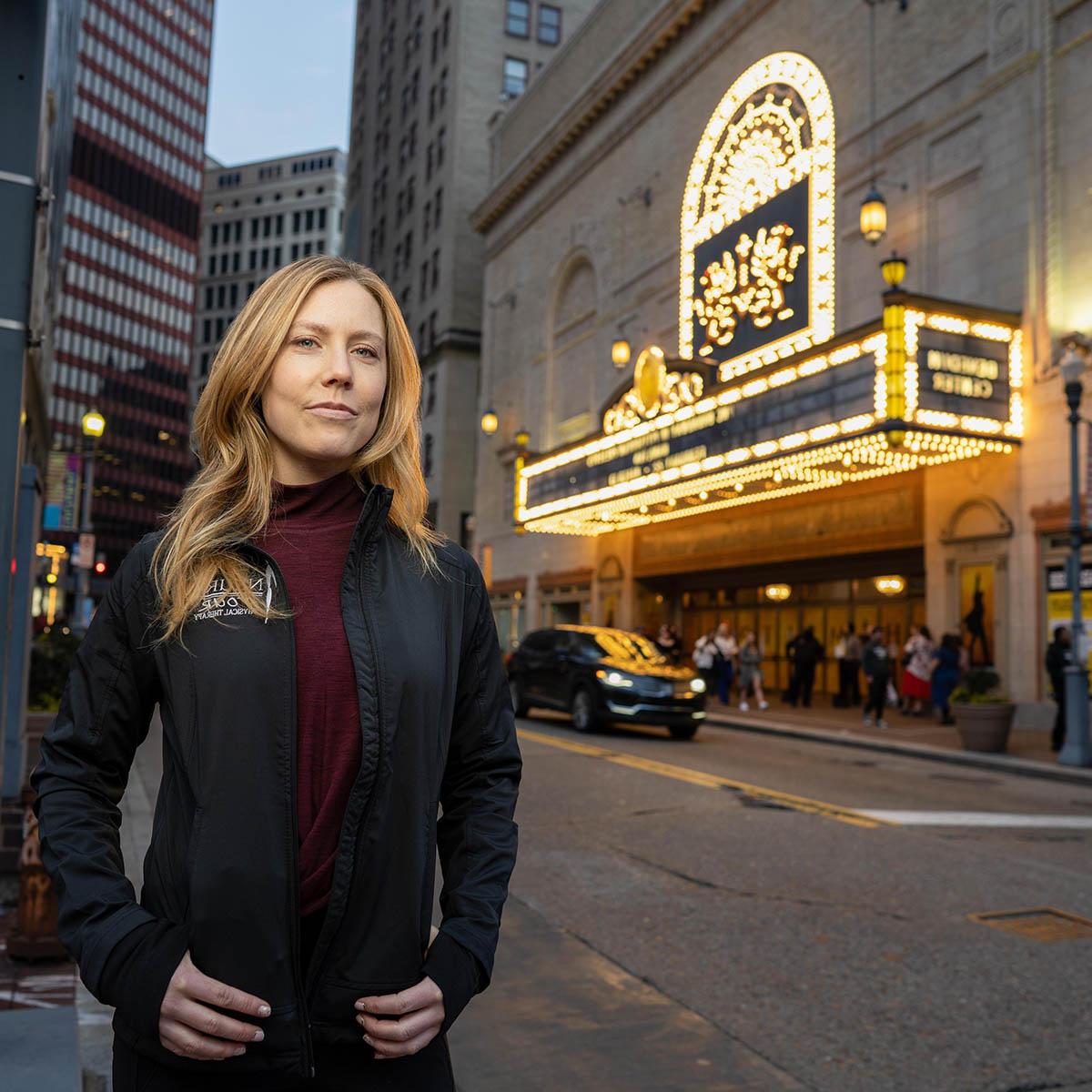 Photo of a woman smiling softly and posing in front of Benedum Center in downtown Pittsburgh