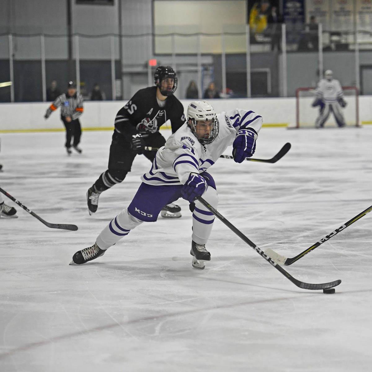 A Chatham hockey player skates with the puck during a game, with an opponent behind