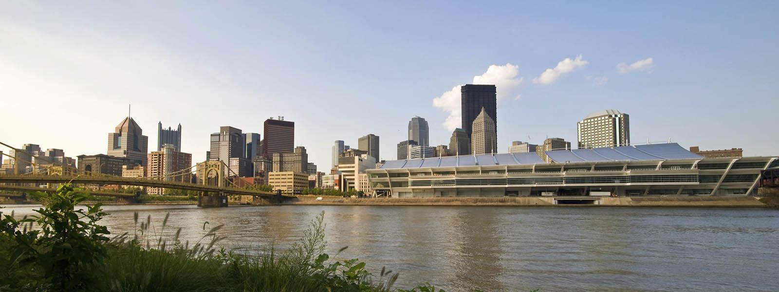 Photo of the Pittsburgh skyline, with a river and yellow bridges