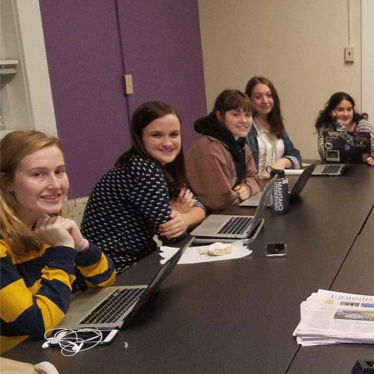 Communique students are seated in a room together, working on their laptops